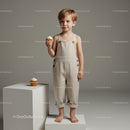 Young boy in beige overalls holding cupcake