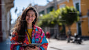 Young Woman Smiling in Colorful Floral Jacket on City Street