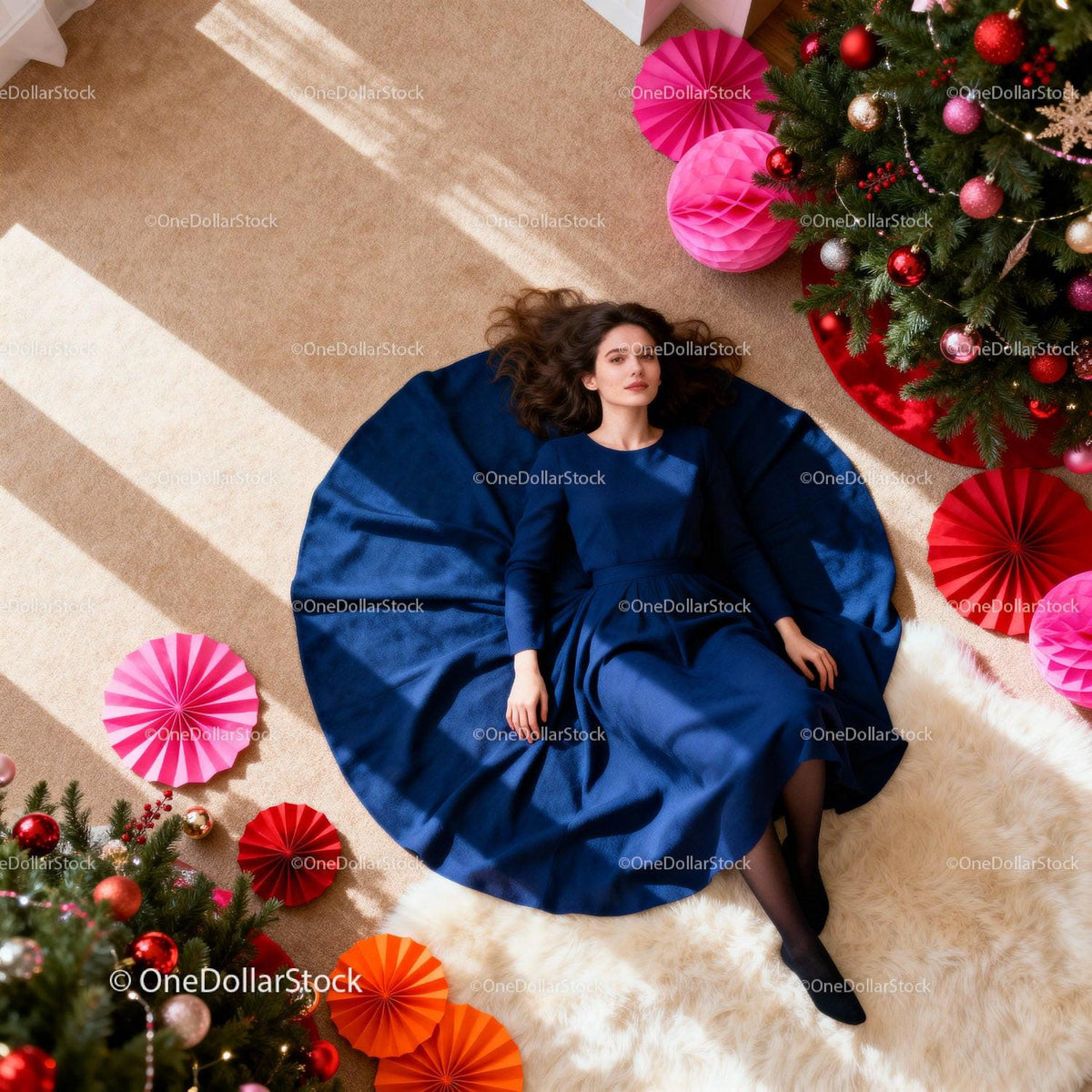 Woman in elegant blue dress lying by festive Christmas tree
