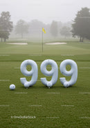Golf balls arranged in 999 on green course with flag