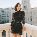 Elegant Young Woman in Black Lace Blouse and Leather Skirt on City Balcony