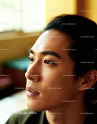 Thoughtful young man reflecting in warm indoor light