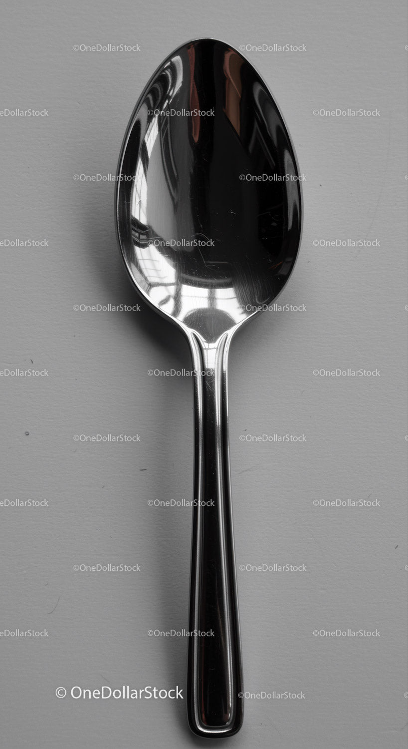Reflective stainless steel spoon on gray surface