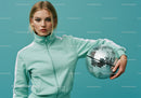 Young Woman in Mint Green Tracksuit Holding Disco Ball in Studio
