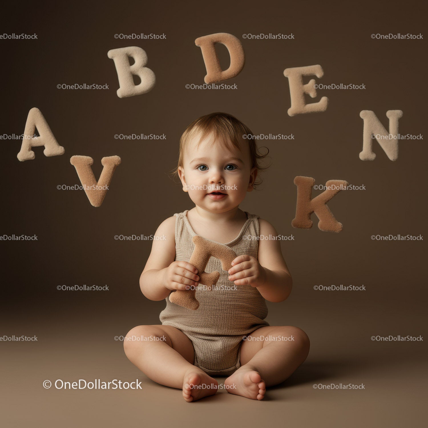 Toddler Sitting with Soft Alphabet Letters in Neutral Room