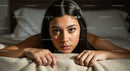 Intimate Portrait of a Young Woman Resting on a Bed in Cozy Bedroom