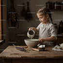 Little girl pouring water into bowl in rustic kitchen