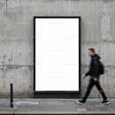 Man walking past blank urban billboard on concrete wall