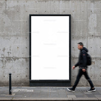 Man walking past blank urban billboard on concrete wall