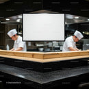 Chefs Preparing Cuisine Behind Blank Kitchen Menu Board
