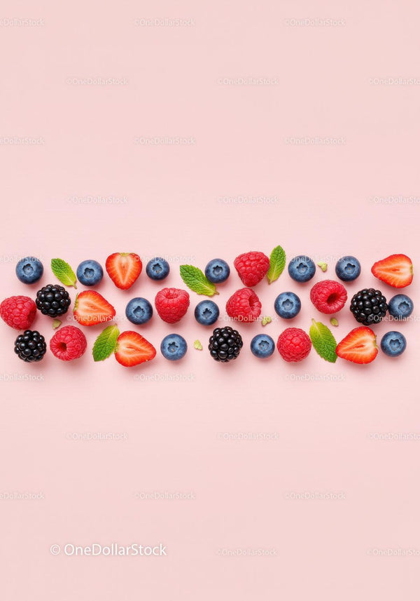 Fresh mixed berries and mint leaves on pink background