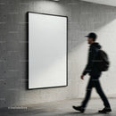 Blurred man walking past large blank poster on concrete wall
