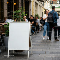 Blank white signboard outside busy street cafe