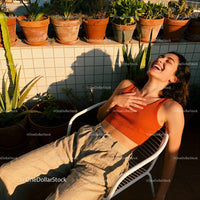 Joyful woman relaxing on chair in sunny garden