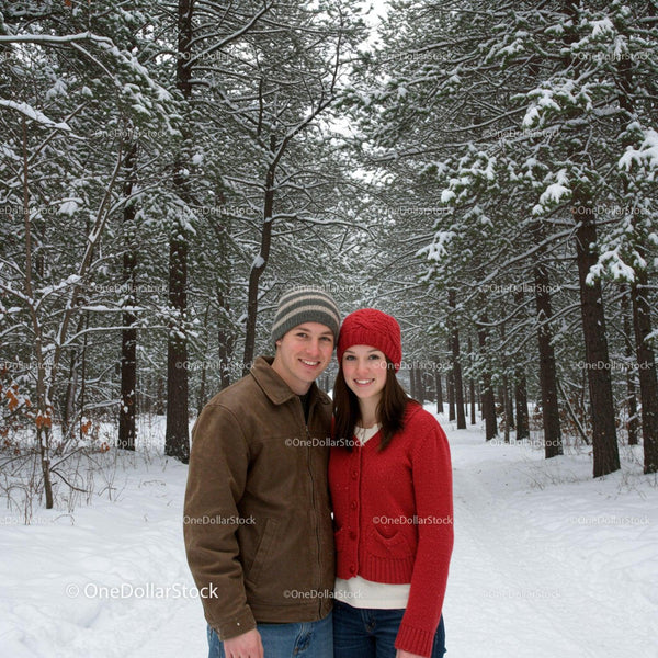 Young couple smiling in snowy pine forest