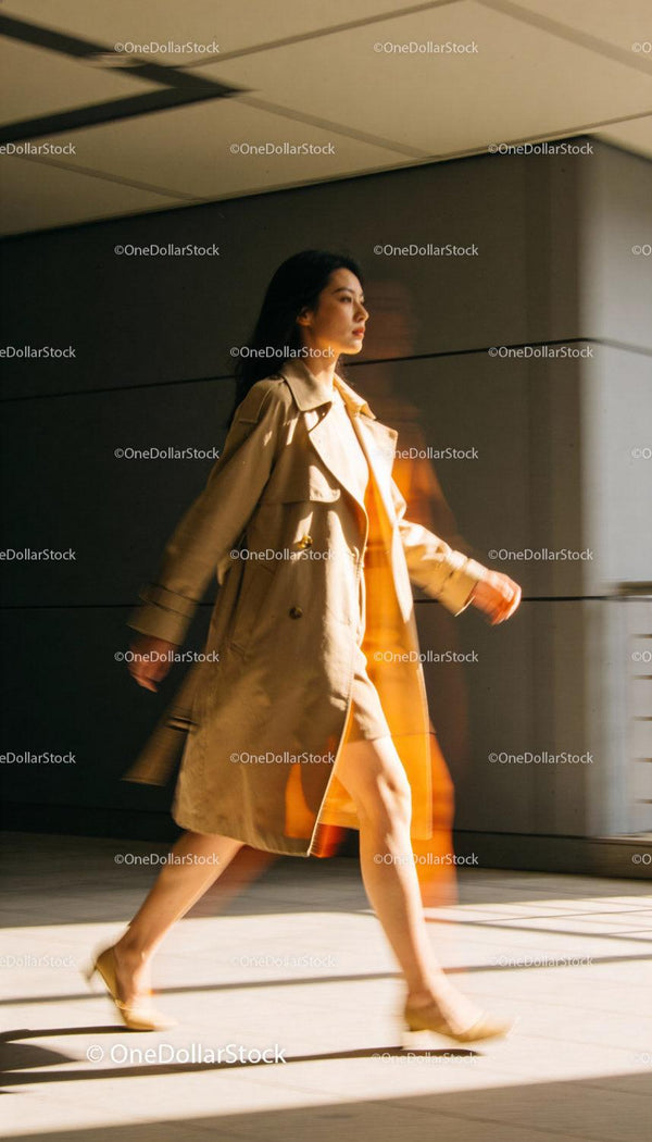 Pewna siebie kobieta w beżowym płaszczu przechodząca energicznym krokiem
