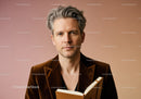 Elegant Mature Man with Gray Hair Reading Book in Stylish Indoor Setting