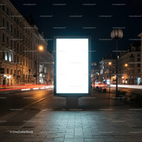 Illuminated blank billboard on city street at night