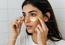 Young Woman Applying Gold Under Eye Patches for Skincare