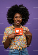 Smiling Woman with Afro Hair Holding Love Sign Against Purple Background
