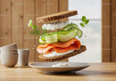Fresh salmon sandwich with cucumber and herbs floating