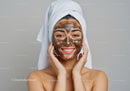Young Woman with Mud Facial Mask Smiling During Spa Treatment