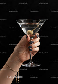 Hand Holding Martini Glass with Olive on Black Background