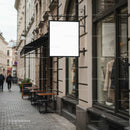 Blank hanging signboard on city street storefront facade