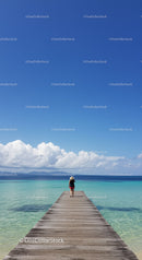 Woman Walking on Pier Over Clear Blue Water Under Bright Sky