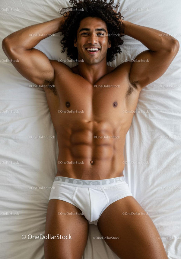 Smiling muscular man relaxing on white bed sheets