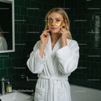 Young Woman Wearing Gold Eye Patches in Spa Bathroom