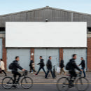 Blurred commuters walking and cycling past blank billboard