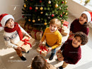 Joyful Children Sharing Christmas Gifts by Tree