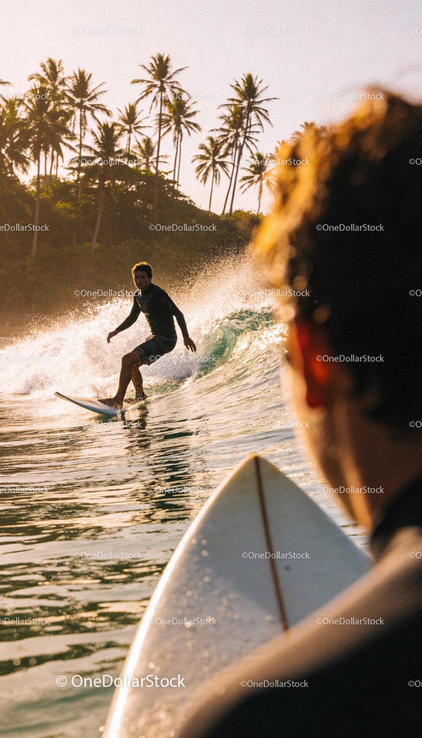 Surfer riding wave with tropical palms at sunset