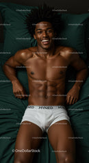 Smiling young man lying on dark green bed sheets