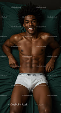 Smiling young man lying on dark green bed sheets