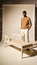 Man in brown sweater posing beside modern beige bench