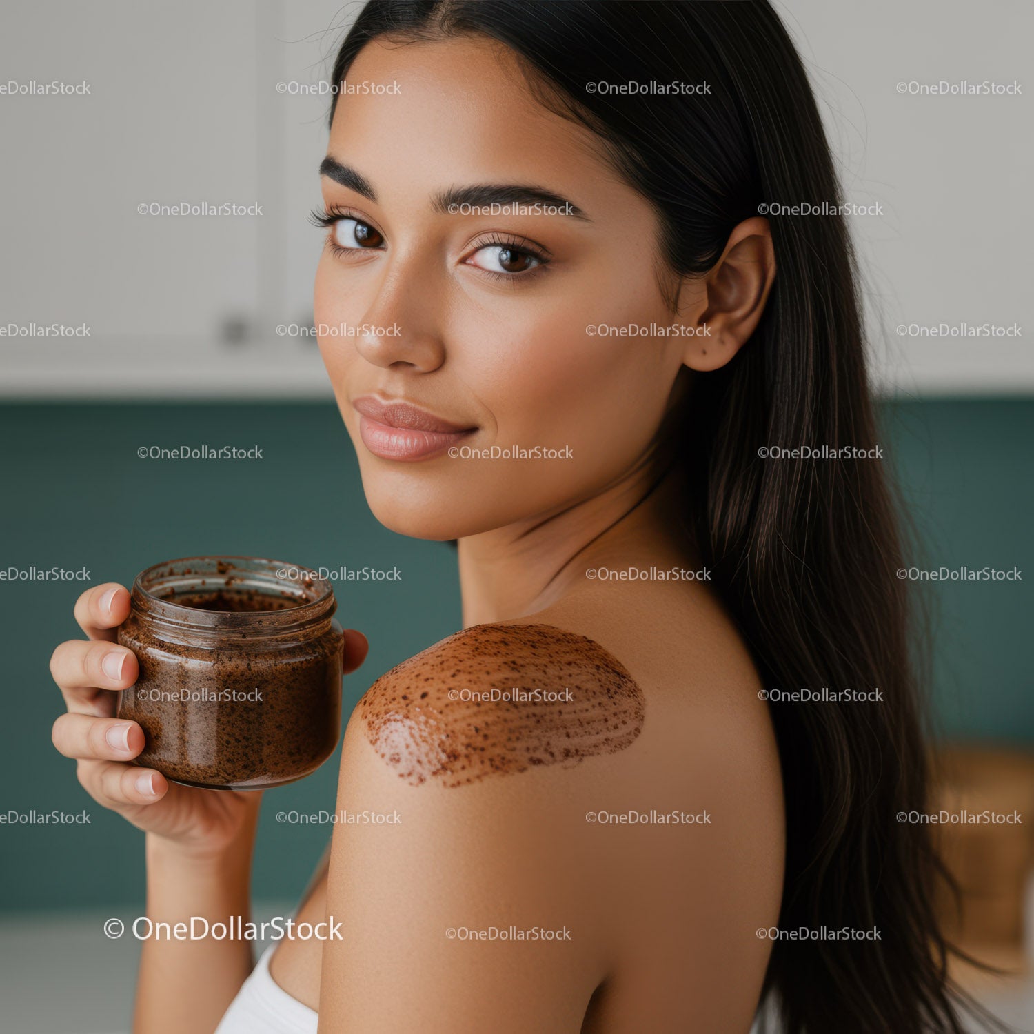 Młoda kobieta nakładająca peeling kawowy na ramiona w celu pielęgnacji skóry