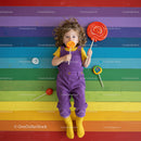 Child Lying on Rainbow Floor with Colorful Lollipops
