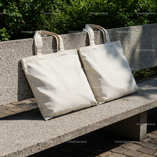 Blank canvas tote bags resting on stone bench outdoors JPG Mockup Image