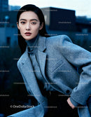 Elegant woman in gray coat posing with urban backdrop