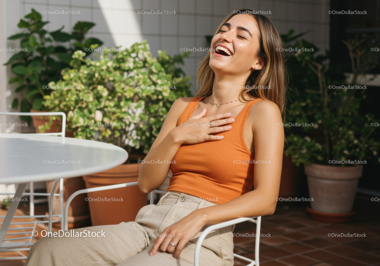 Joyful young woman laughing outdoors with plants and sunlight