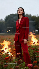 Confident woman in red suit standing in burning field