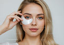 Young Woman with Blue Eyes Applying Eye Mask for Skincare Treatment