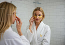 Woman Applying Gold Eye Patches During Facial Treatment in Spa