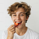 Smiling Boy Enjoying Strawberry Bite with Bright Expression