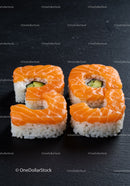 Fresh salmon sushi rolls with avocado on black plate