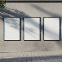 Three blank posters hanging on textured concrete wall