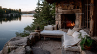 Cozy lakeside patio with outdoor fireplace and scenic forest view