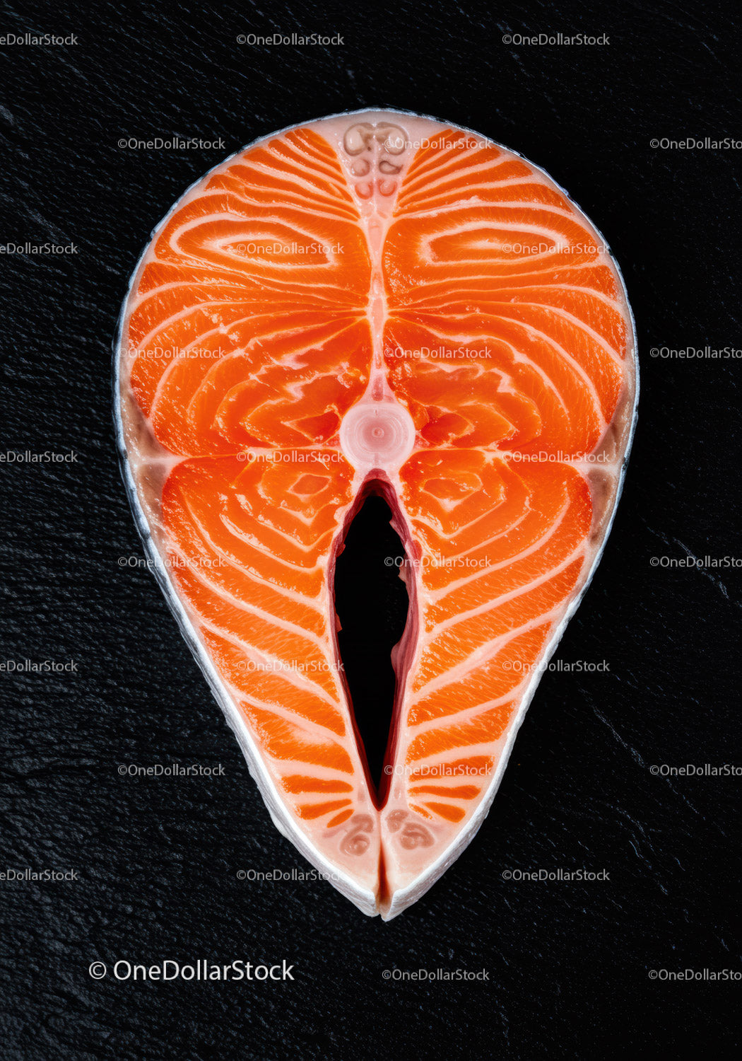 Fresh salmon steak slice on black textured surface